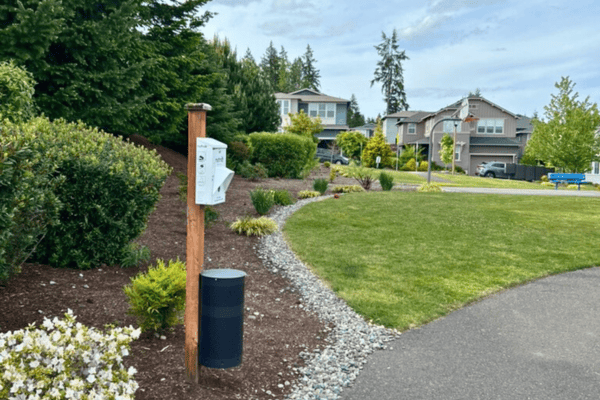 Pet waste station along a landscaped HOA trail in Kitsap County, showing ongoing dog waste removal service for neighborhoods.